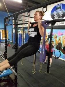 A woman does a pull up at Elite Edge.