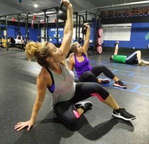 A photo of three people working out at Elite Edge utilizing kettlebells.