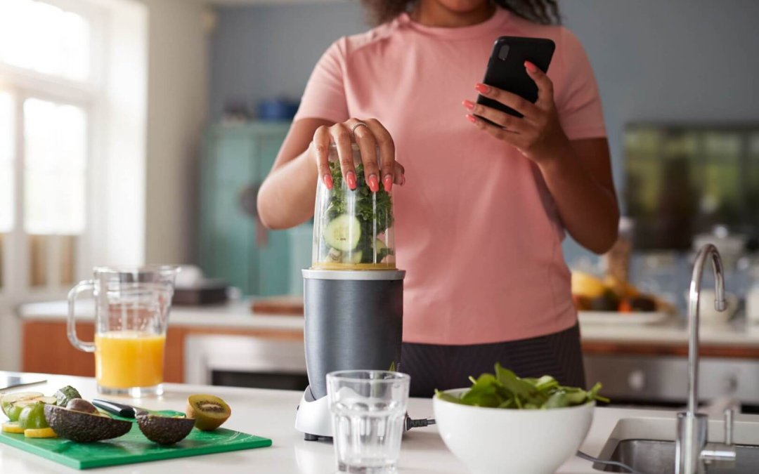 Close Up Of Woman Using Fitness Tracker To Count Calories For Post Workout Juice Drink She Is Making