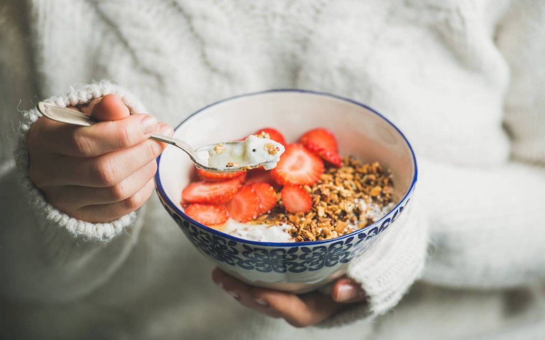 Healthy breakfast yogurt, granola, strawberry bowl in woman’s hands